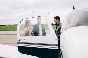 Young Male Pilot Taking to Caucasian Couple in Front of Small Ai
