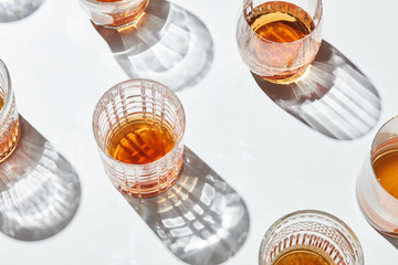 Tumblers with whiskey on white background.