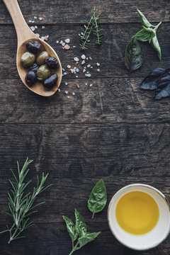 Food: Wooden background with a spoon of olives,himalayan salt,ol