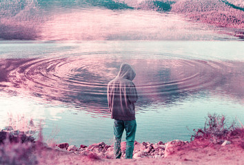 Young hooded man thinking and overlooking beautiful lake