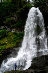 Man standing at the base of a rushing waterfall 