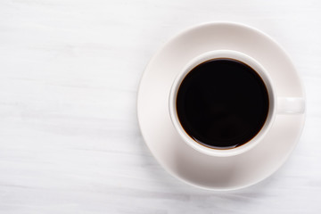 Cup of black coffee on white table, top view