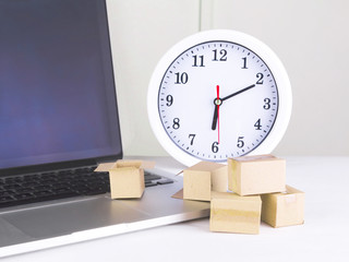 Online delivery or shopping concept. Packaging box on a laptop with background of a clock.
