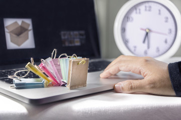 Concept of online shopping. Finger clicking mouse pad with paper bag on a laptop.