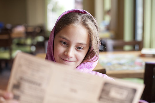 Ten year old girl looks at a menu in a cafe
