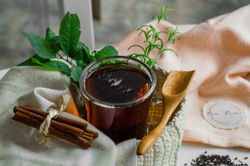 Transparent Cup of tea brewed with adjacent wooden spoons. Cinnamon sticks. Tea time. Tea leafs,...