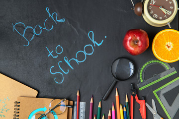 Chalk on black chalkboard "back to school" and stationary