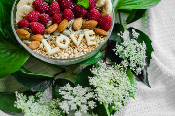 Eating healthy breakfast bowl. The word LOVE in a plate with a healthy meal. Raspberry, Banana, Nuts. Vegetarian food concept