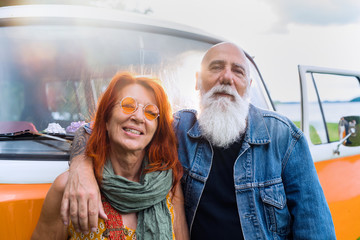 An old hipster couple posing in front of their camper van 