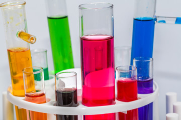 Experiments in mixing chemical substances into glass tubes with a microscope in a science lab with a white background..
