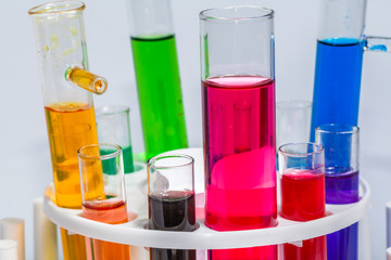 Experiments in mixing chemical substances into glass tubes with a microscope in a science lab with a white background..