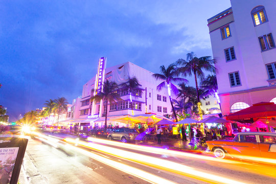 Ocean Drive scene at sunset with lights, palm trees, cars and people having fun, Miami beach. Art Deco style hotels and restaurants at sunset on Ocean Drive, world famous destination for its nightlife