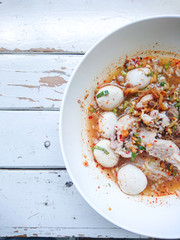 Closeup Spicy TOM YAM Pork Noodles Soup with Pork Balls, chilly pasted and lime juice / Noodles in Thai spicy tom yum soup with pork
