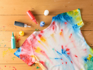 T-shirt painted in tie dye style on a brown wooden table.