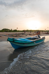 Sunset view of small fishing boat on Nilaveli beach in Trincomalee Sri Lanka Asia