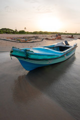 Naklejka na ściany i meble Small fishing boat at sunset on Nilaveli beach in Trincomalee Sri Lanka Asia