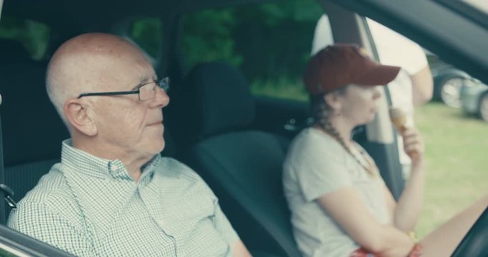 Senior man sitting in car with his adult daughter eating ice cream