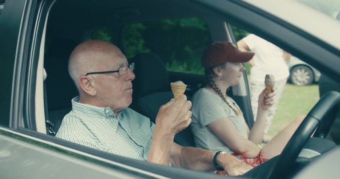 Senior man and his daughter eating ice cream in car