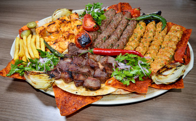 Fast food. Eastern food. Shish kebab, lyulya-kebab, shaverma, pita gyros. Dishes of oriental cuisine lying on pita bread and decorated with greens and vegetables, sauces and French fries. - obrazy, fototapety, plakaty