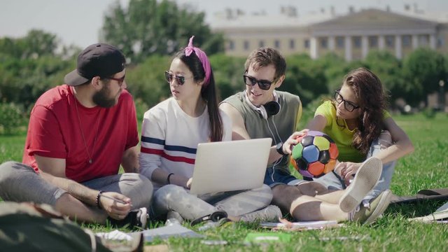 Students work together on computer in the park.