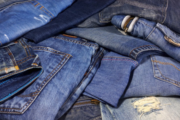 A pile of different jeans trousers as background.