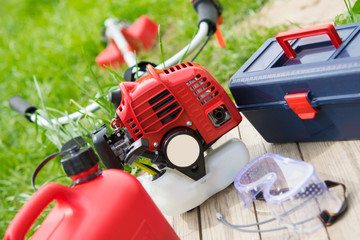 Fototapeta premium a set of tools for the care of green lawn, red chainsaw, fuel cans, a tool for adjustment.