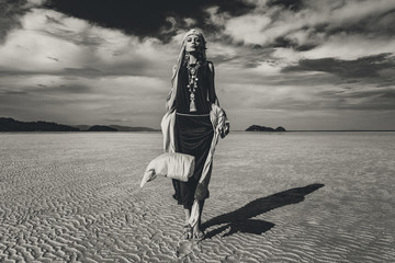 Fototapeta premium beautiful young stylish woman walking on low tide at sunset. black and white. fashion concept