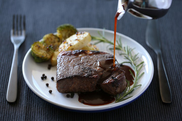 Beef steak isolated on white plate with rosemary and black pepper sauce 