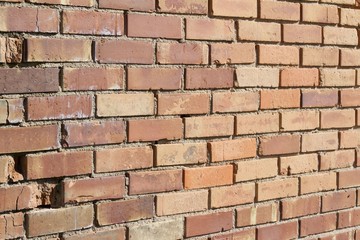 Obraz premium Decomposing brick wall has interesting old bricks in varying hues of brown and tan