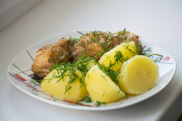 Slices of grilled sea bass with boiled potatoes on the plate.