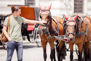 Tourist man enjoying a stroll through Vienna and looking at the two horses in the carriage