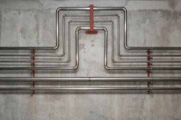 Pipes made of stainless steel on a concrete wall background.