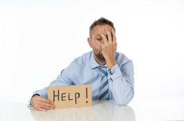 Young attractive frustrated and tired caucasian businessman holding help sign message exhausted, sad under pressure and stress isolated on white in unemployment depression overwork concept