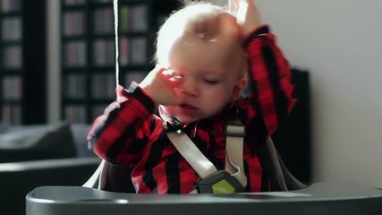 Portrait of sleepy baby boy yawning in a high chair