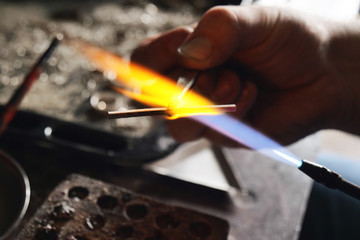 Close up of a goldsmith while he is working to make a diamond ring. Concept: jewelry, silver, gold
