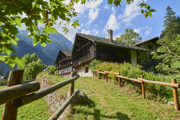 Fototapeta na wymiar Sentiero di Montagna costeggiato da uno steccato porta ad chalet di montagna in Val d'Aosta