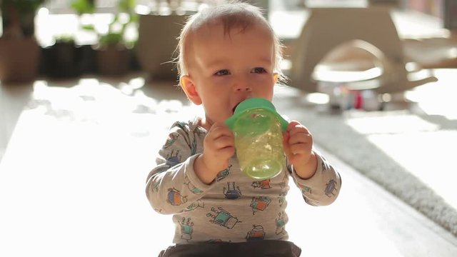 Portrait of a cute toddler drinking water from the bottle cup