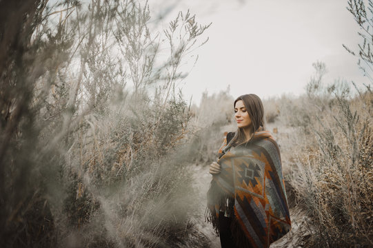 Pretty hipster traveler girl in gypsy look in desert nature, looking at camera and smiling.  Artistic photo of young hipster traveler girl in gypsy look, in Coachella Valley in a desert valley in Sout
