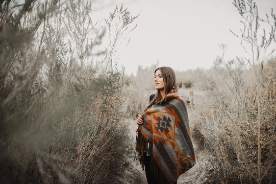 Pretty hipster traveler girl in gypsy look in desert nature, looking at camera and smiling.  Artistic photo of young hipster traveler girl in gypsy look, in Coachella Valley in a desert valley in Sout