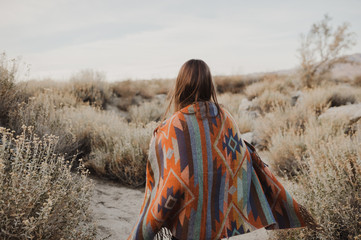 Back side of boho woman in the desert nature.  Artistic photo of young hipster traveler girl in...