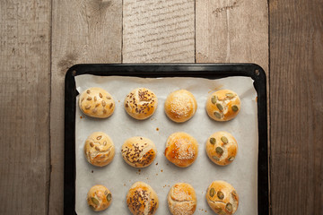 The homemade bread rolls with sesame seeds hamburger with sesame, pumpkin, flax, sunflower seeds on the tray, concept of burger and homemade food. Mini challah