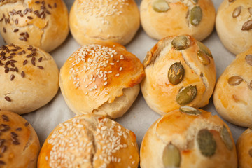 The homemade bread rolls with sesame seeds hamburger with sesame, pumpkin, flax, sunflower seeds on the tray, concept of burger and homemade food. Mini challah