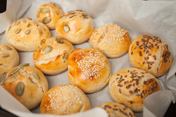 Fresh homemade Hamburger Buns, Brioche with sesame, pumpkin, flax, sunflower seeds on the tray, concept of burger and homemade food. Mini challah