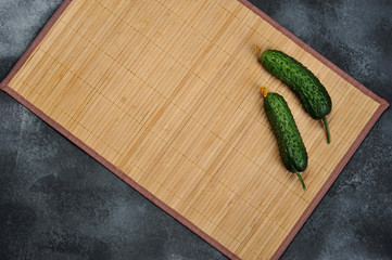 two young cucumbers on a thorny background