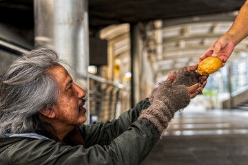 Homeless male with happy face showing hands to recieve bread from donator hand