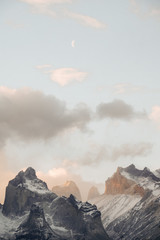 Snow-covered peaks of unusual shape in the clouds with a month. Chile. Torres del Paine