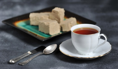 tea in a mug with a golden edge and a saucer and halva cut into pieces