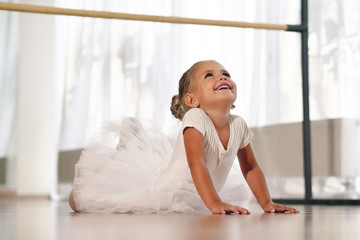 Portrait of a beautiful very young girl, in a dance school wearing a white tutu, she trains alone to learn new dance steps. Concept of: ambition, education, elegance and love for the dance...