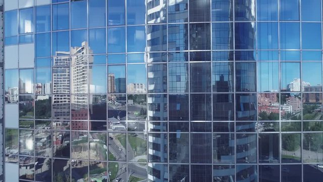 reflection in the windows of a corporate building. Aerial video of Business centre. The camera flying up the skyscraper's facade. The shot is close to the skyscraper