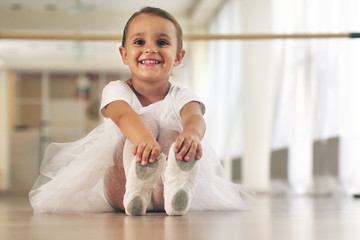 Porträt eines schönen, sehr jungen Mädchens, das in einer Tanzschule ein weißes Tutu trägt und alleine trainiert, um neue Tanzschritte zu lernen. Konzept von: Ehrgeiz, Bildung, Eleganz und Liebe zum Tanz...